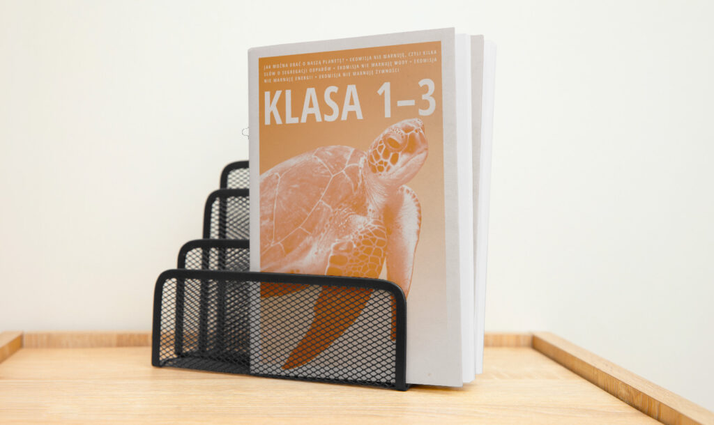 edukacyjny album z żółwiem na okładce, w pomarańczowej kolorystyce Banków Żywności