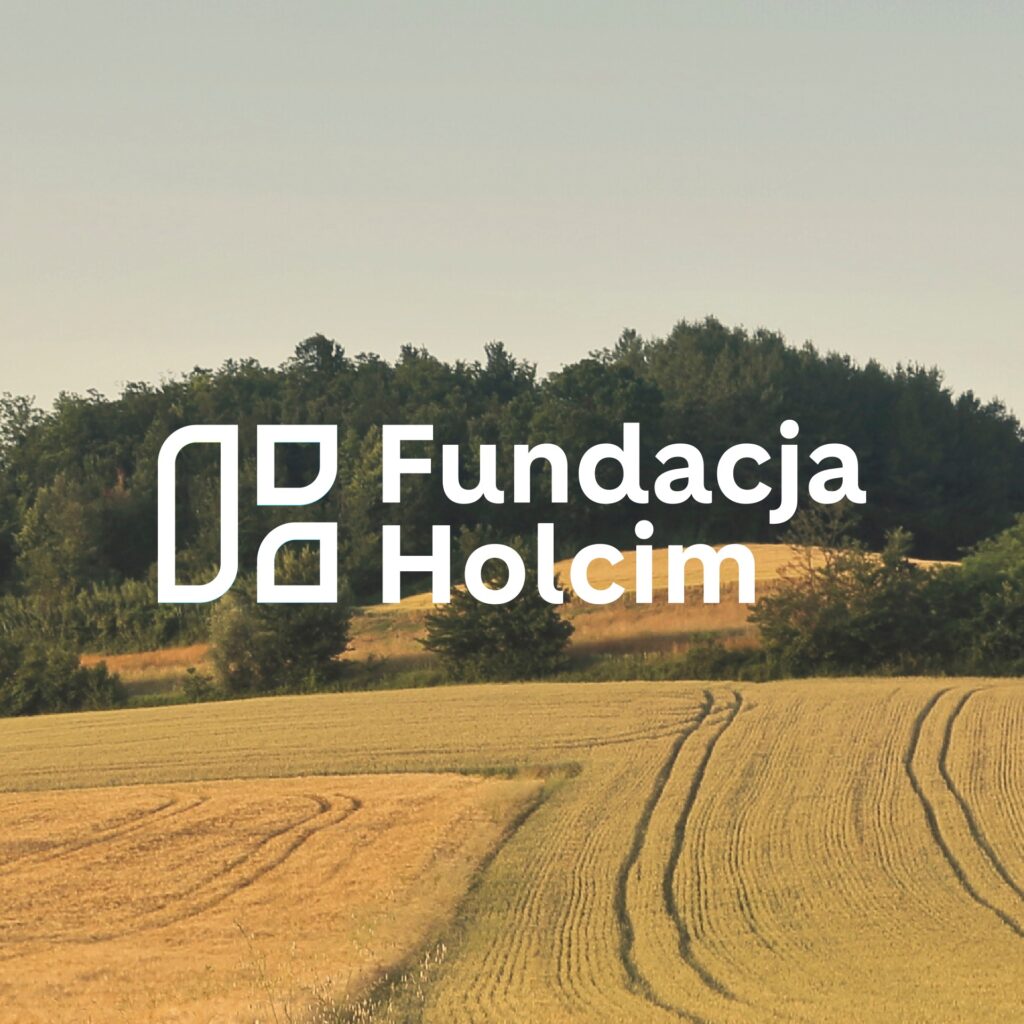 logo Fundacja Holcim na tle zdjęcia pola uprawnego i lasu